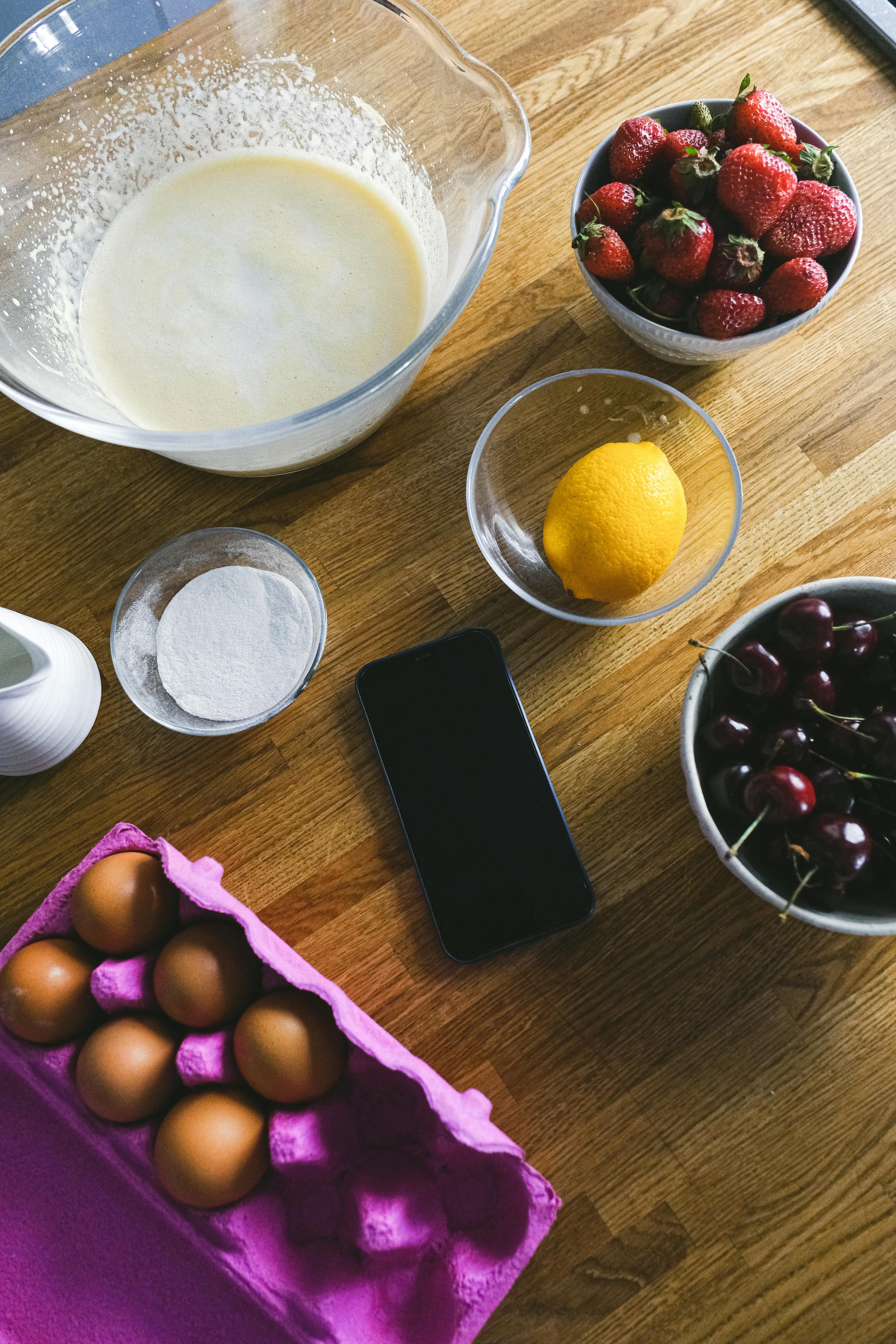 Phone at the center of ingredient prep on a wooden table.